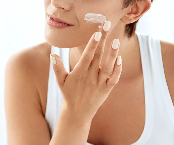 woman applying moisturizer to face