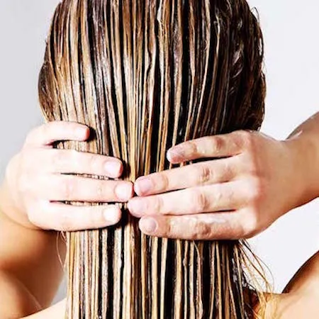 woman applying conditioner to wet hair