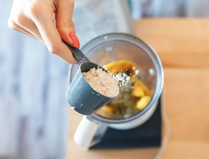 Person adding protein to blender