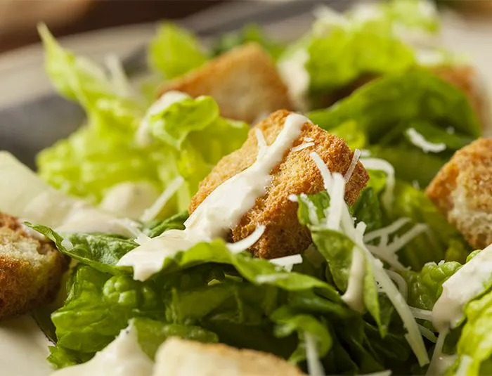 Caesar salad with dressing drizzled on