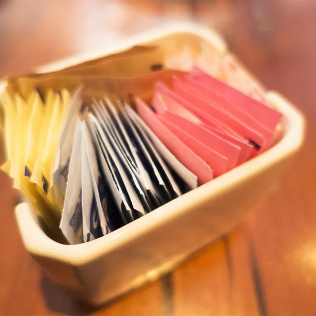 packets of artificial sweetener in holder on table