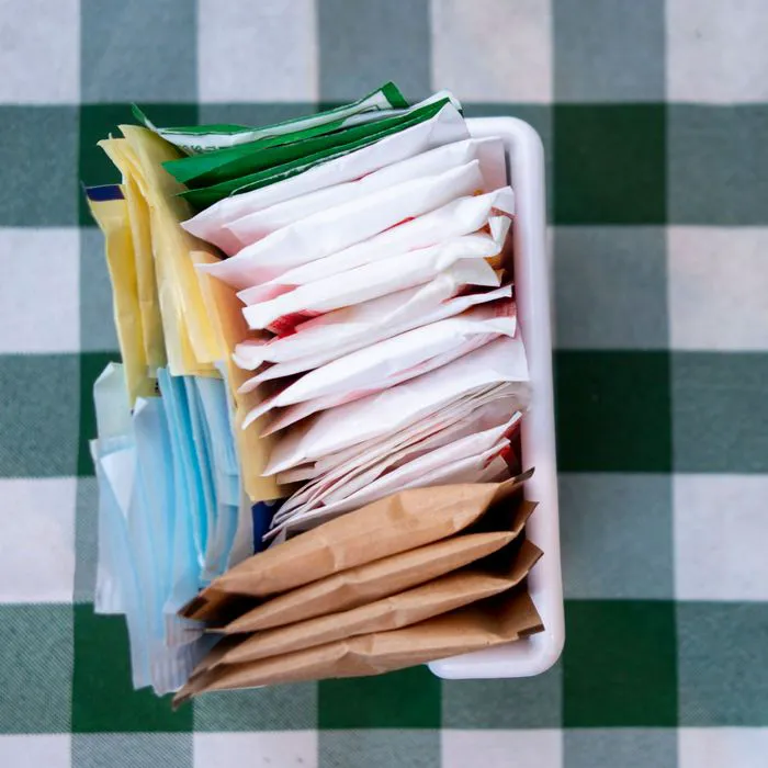 artificial sweeteners in container on green checkered tablecloth