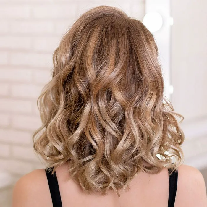 dirty blonde hair behind salon wavy hair shiny curls black straps