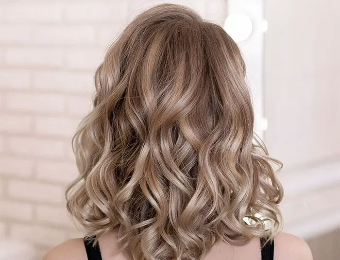 shorter bouncy curls back of model's head curly wavy brown hair highlights salon