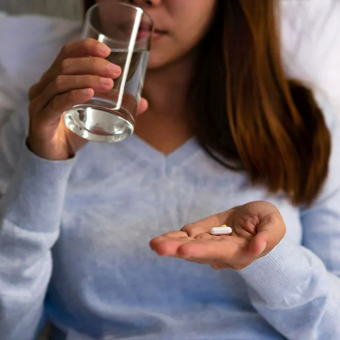 woman taking supplement in bed