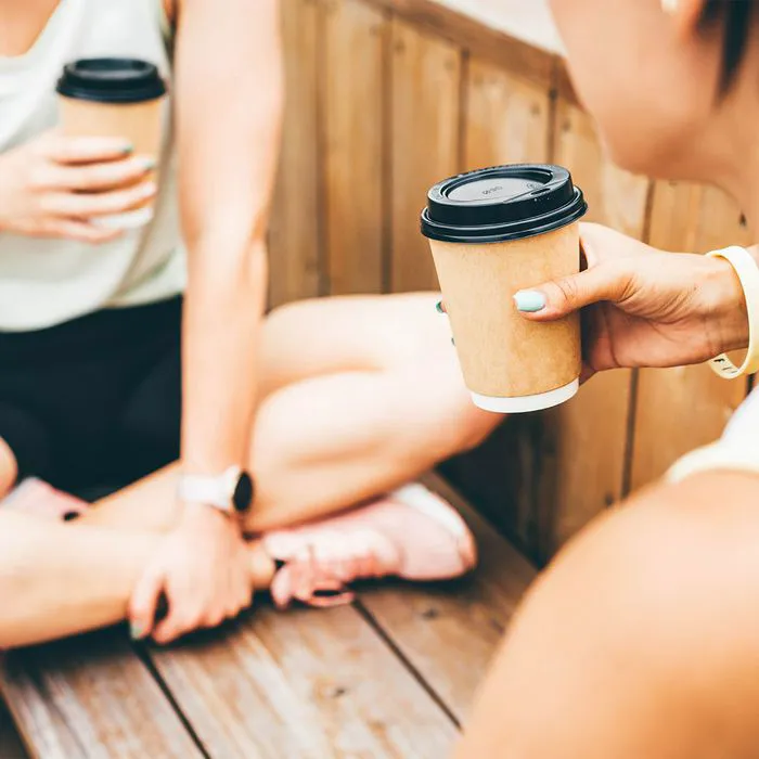 woman drinking coffee from to-go cups after workout