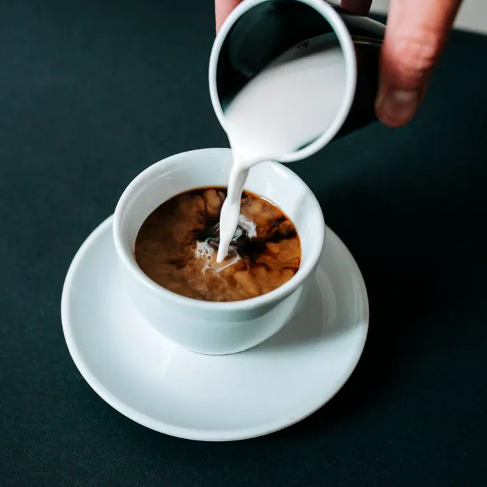 coffee creamer being poured into coffee