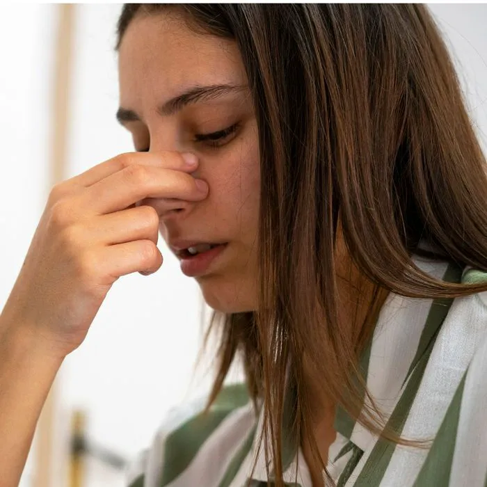 woman holding nose