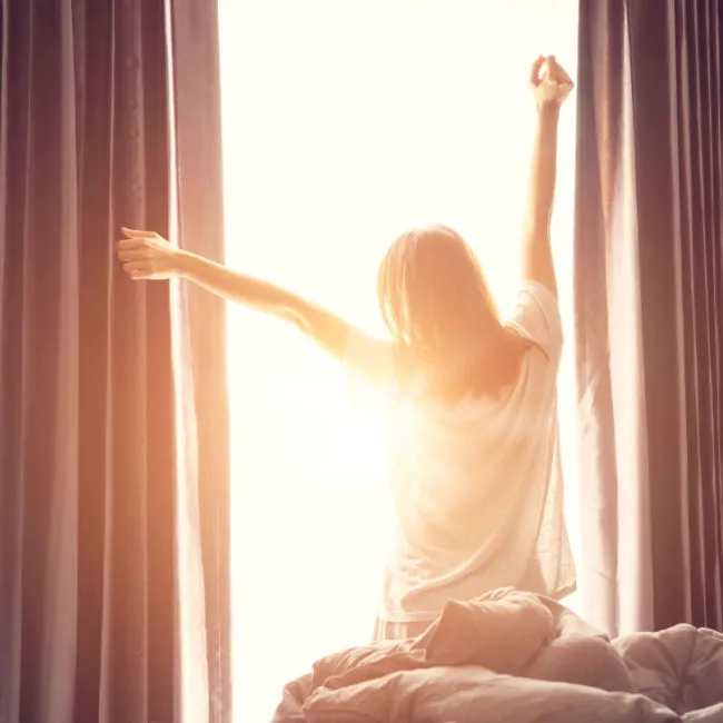 woman stretching in front of window in morning