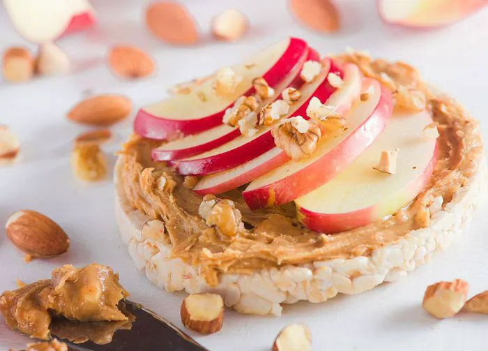 "Almond butter spread on a rice cake topped with apple slices"