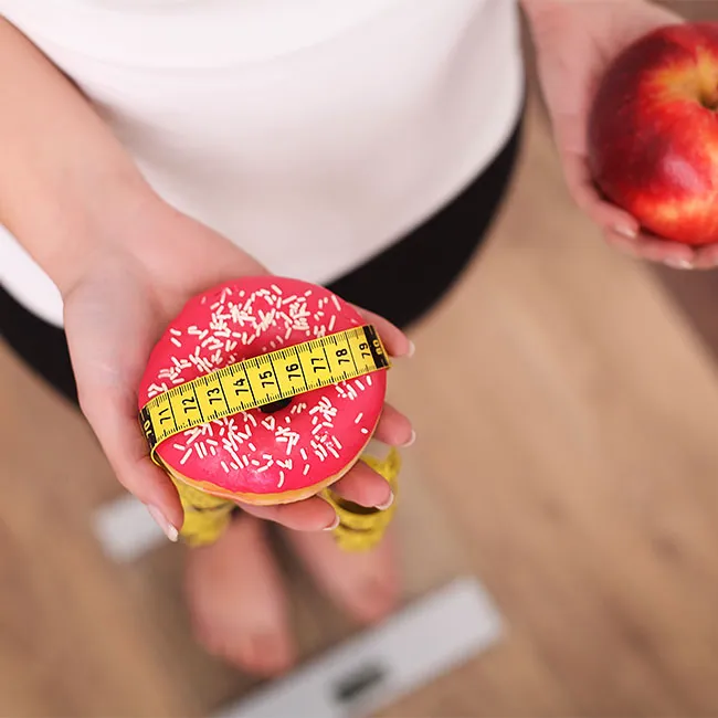 woman standing on scale with donut