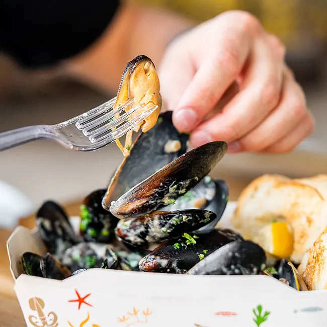 "Person enjoying a meal of mussels and bread"