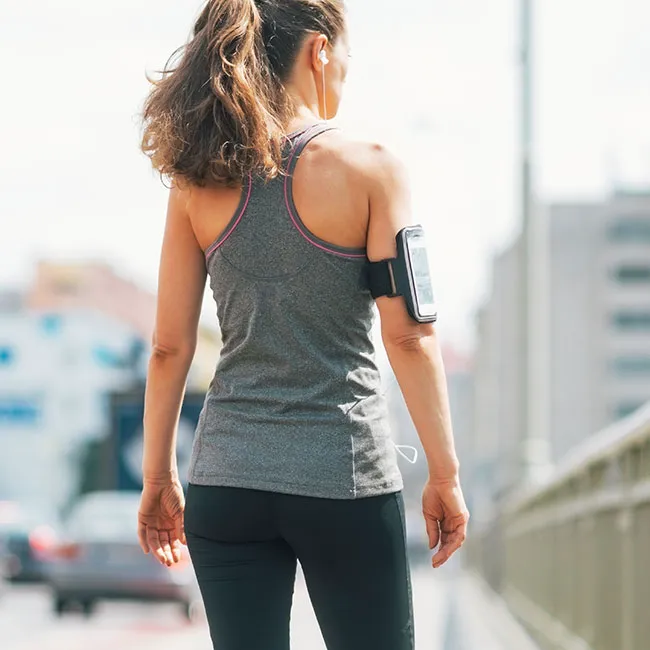 "Woman wearing leggings and earphones walking in the city"