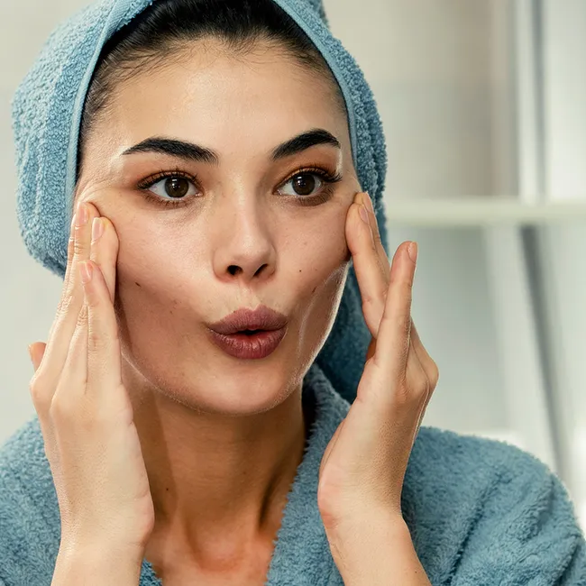 Woman practicing mirror face yoga for relaxation.