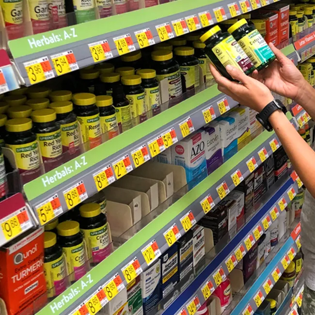 "Woman holding vitamins in the pharmacy aisle"