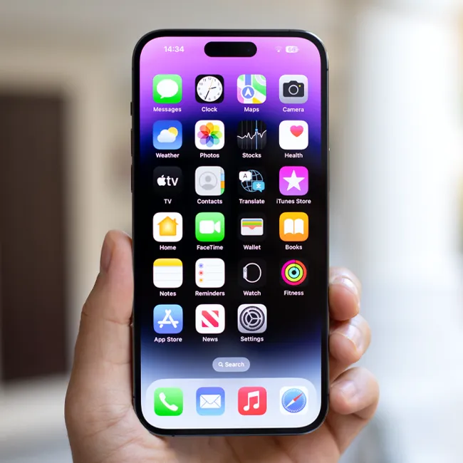 Man holding an iPhone 15 Pro Max showing the iOS 17 home screen