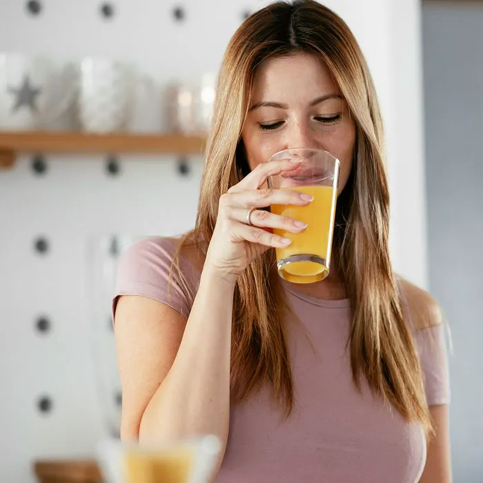 Woman enjoying a glass of orange juice in the morning.