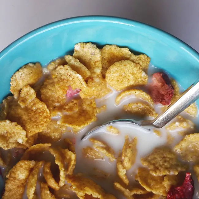 "A breakfast plate with scrambled eggs, sausage, and tomatoes"