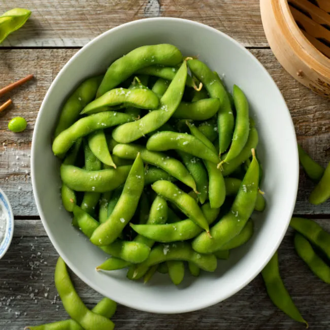 "Bowl of edamame on a wooden table"
