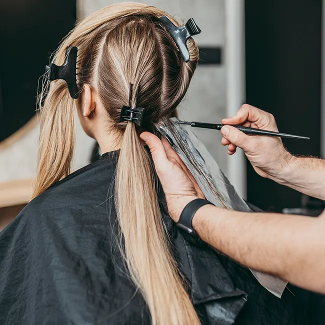 Close-up of hair being dyed in a salon setting.