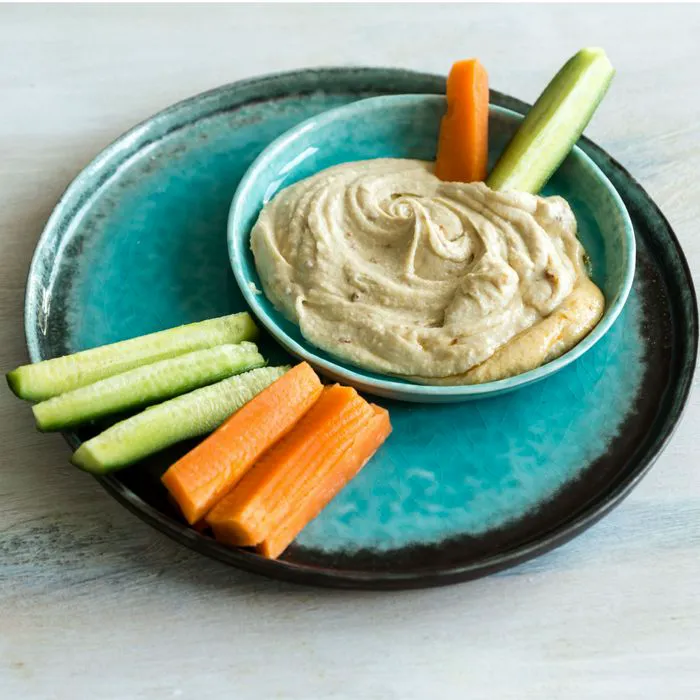 "Hummus served with vegetable sticks"