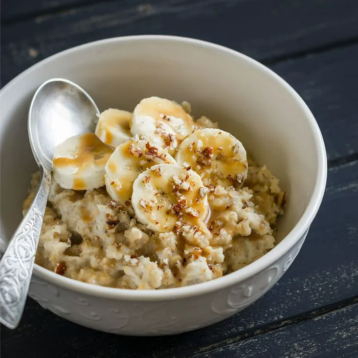 Oatmeal topped with bananas in a white bowl for healthy breakfast.