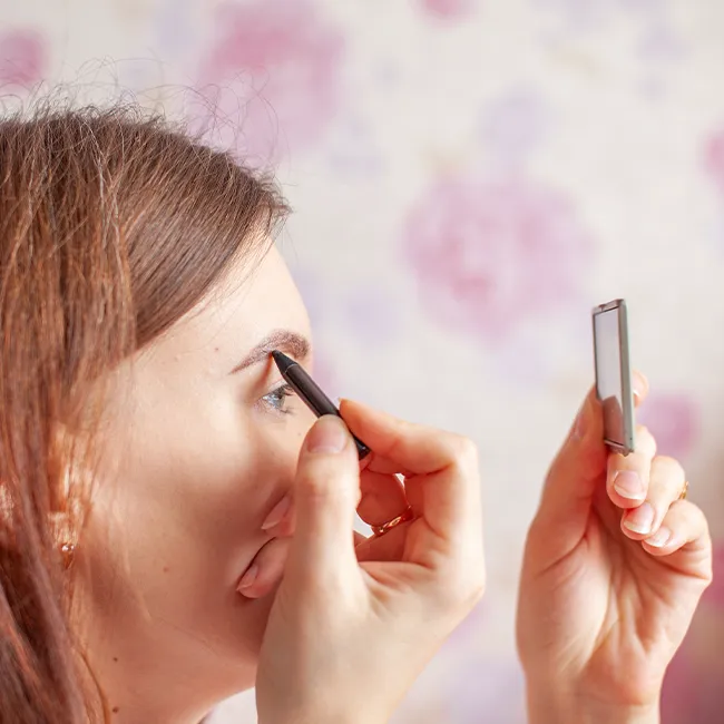 Woman filling in her eyebrows for a defined look.