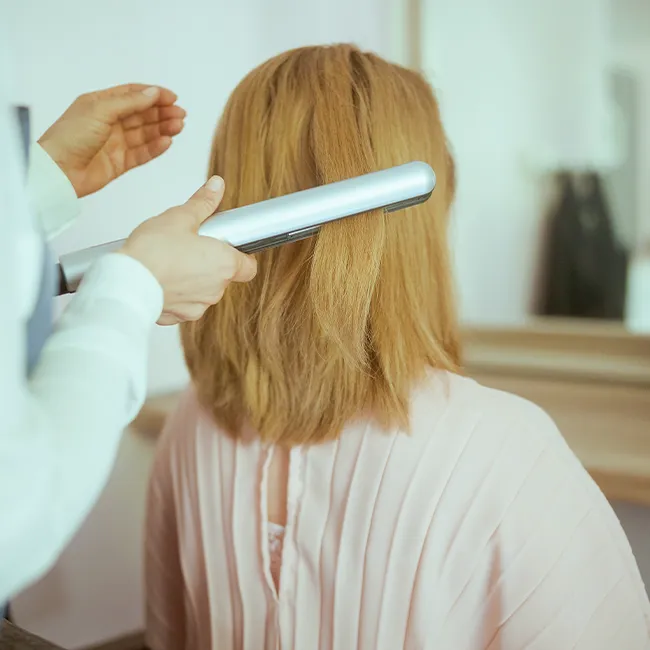Woman getting her hair styled to perfection in salon.