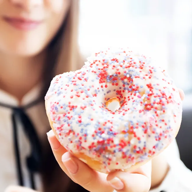 "Woman holding a donut and smiling"