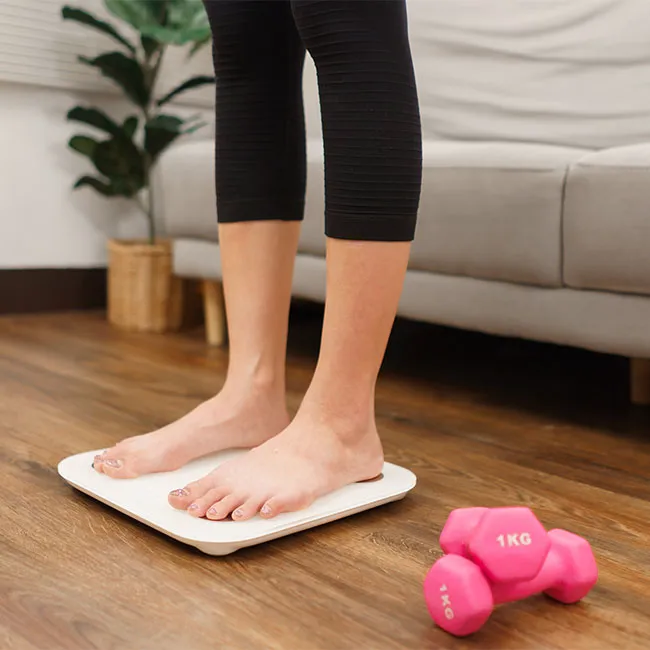 Woman standing on a scale looking pleased with her weight