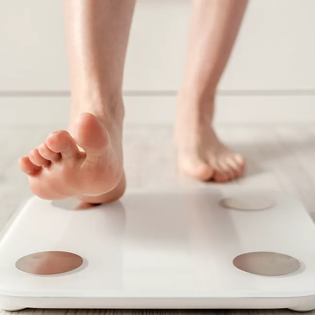 "Woman stepping onto scale to track weight loss"