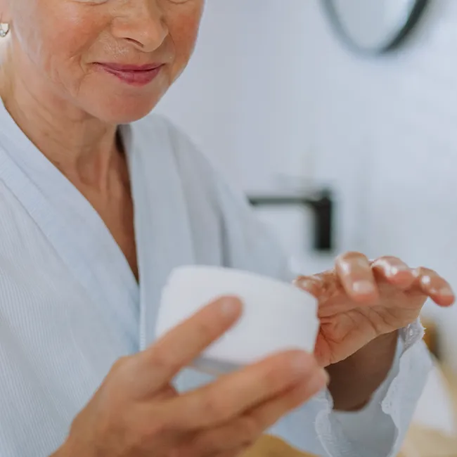 Woman applying neck cream for firm skin.