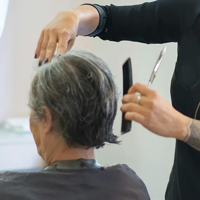 Woman with grey hair getting a stylish haircut.